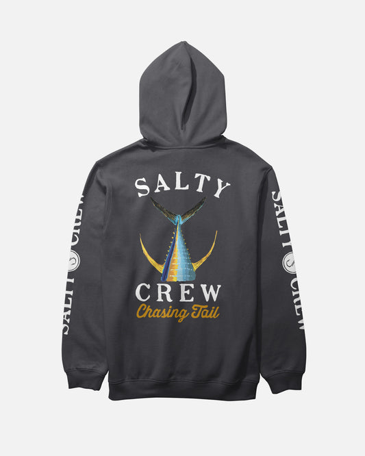 The Salty Crew Tailed Fleece Hoodie - Black features a dark gray hood, kangaroo pocket, white SALTY CREW sleeve prints, and a bold blue and yellow fish tail graphic with “Chasing Tail” on the back.