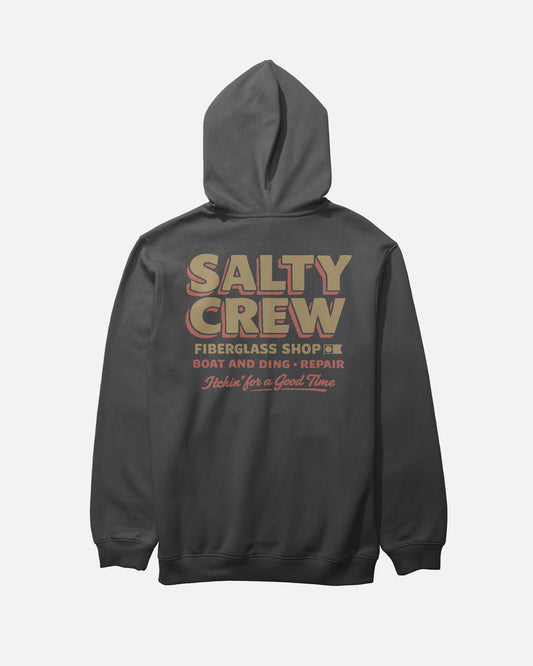The Salty Crew Fiberglass Heavyweight Fleece in washed black features a bold beige SALTY CREW logo on the back with "FIBERGLASS SHOP, BOAT AND DING REPAIR, Itchin for a Good Time" in beige and red lettering.