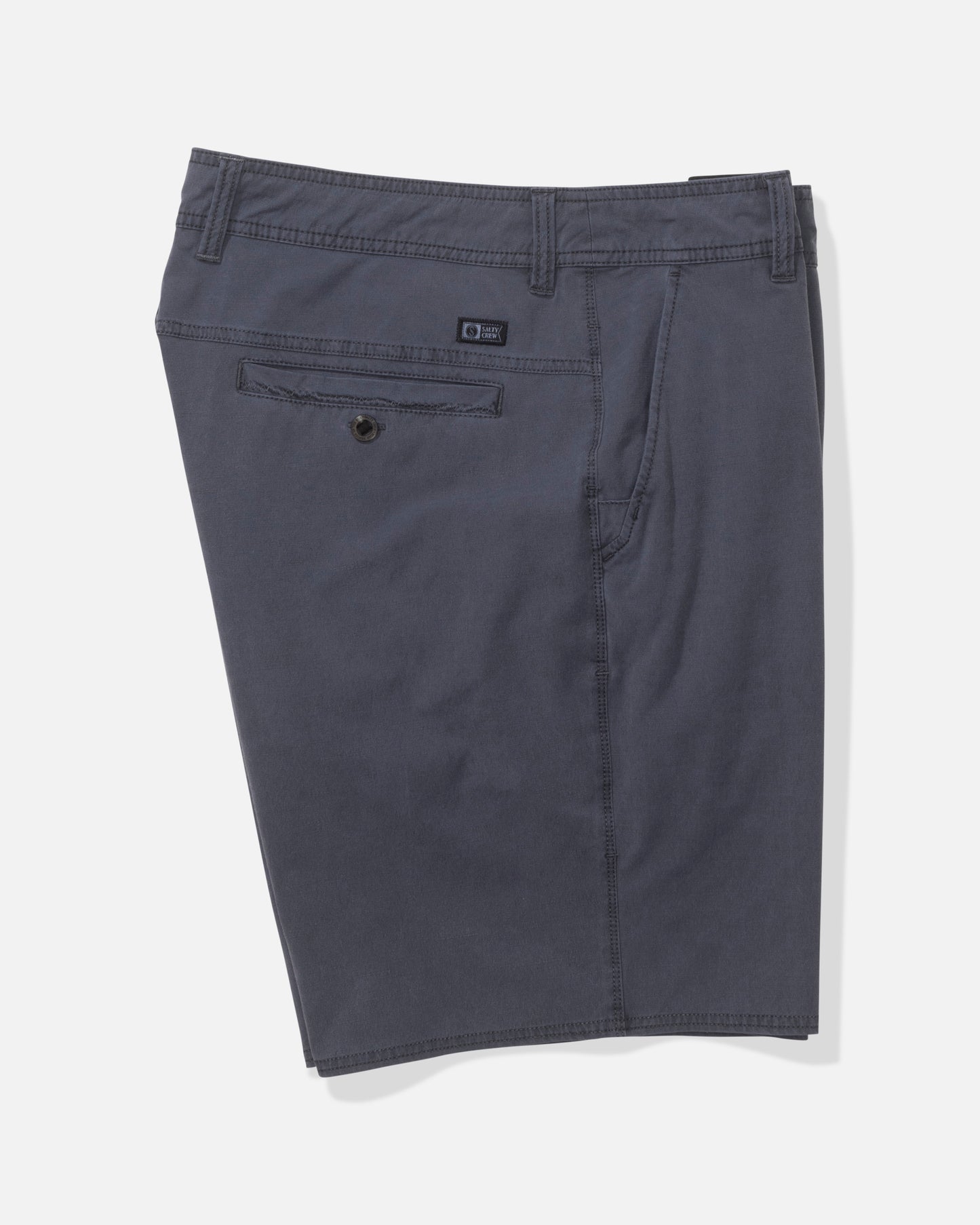 The Salty Crew Transom 19" Overdye Short in Magnet features dark blue color, belt loops, a buttoned back pocket, subtle stitching details, and comfortable 4-way stretch fabric. Shorts are displayed flat against a plain white background.