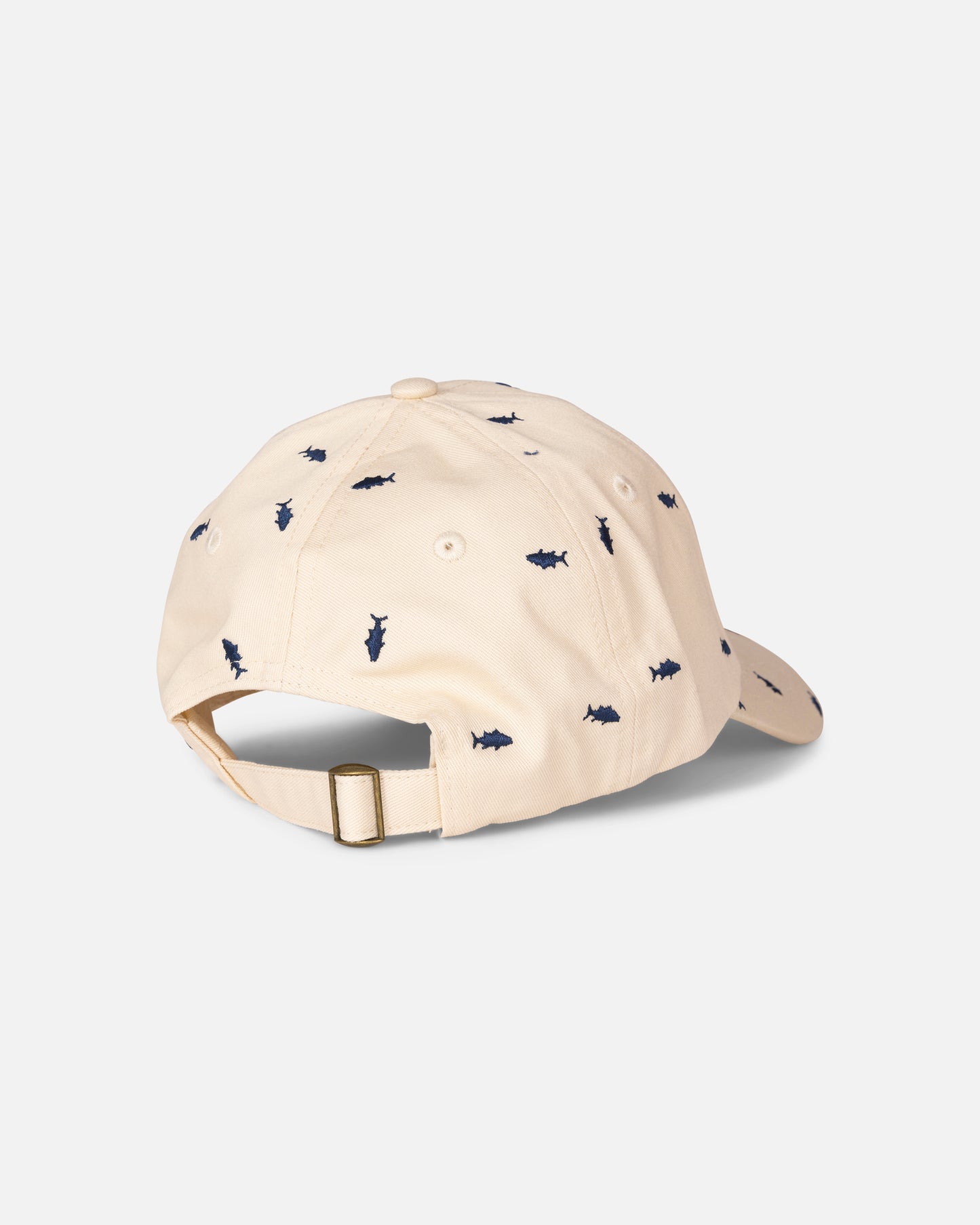 The Salty Crew Nice Catch Hat in Off White is an adjustable cotton cap featuring a brass buckle at the back and small navy shark silhouettes embroidered throughout the fabric.