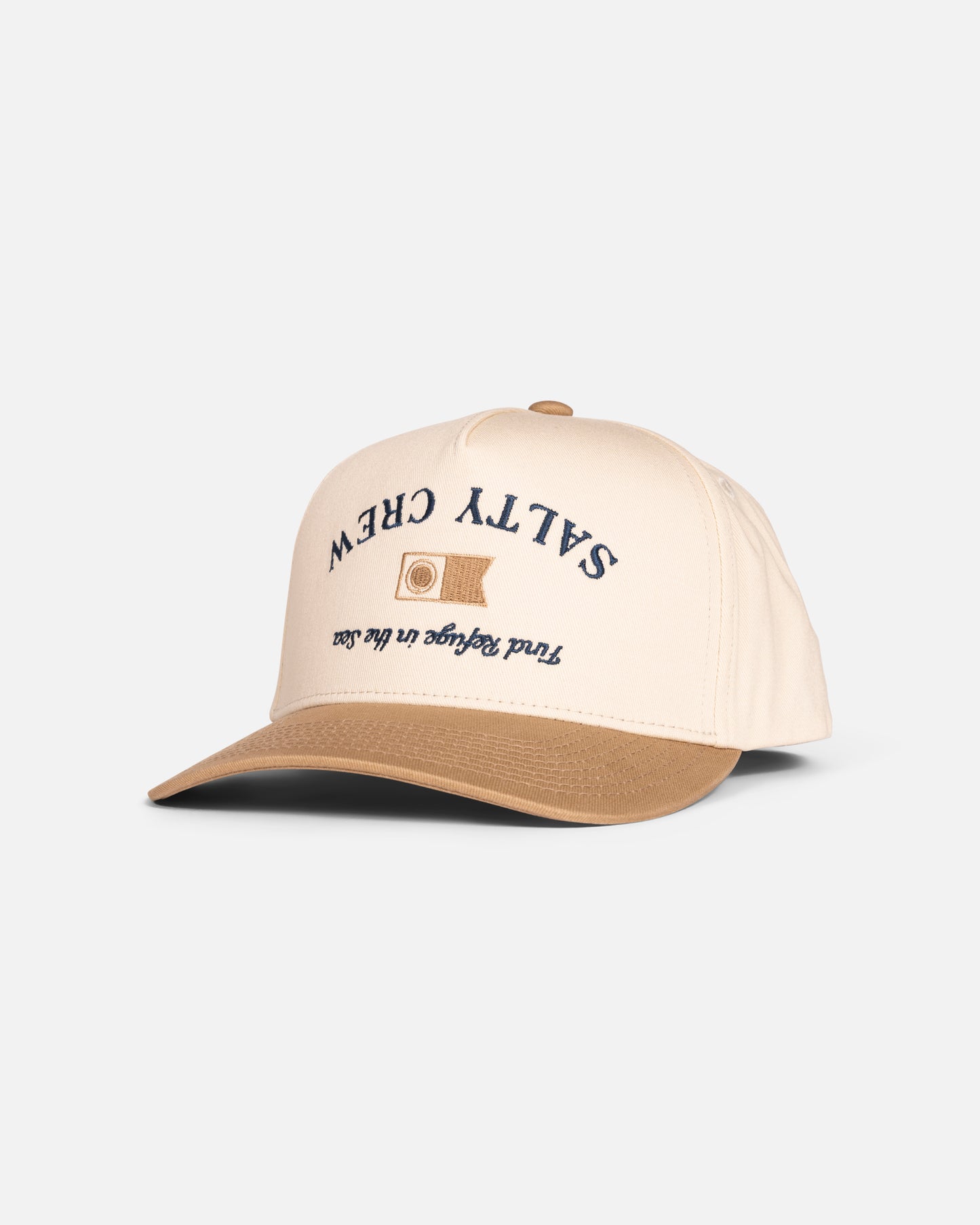 The Salty Crew Upsidedown Crew Snapback in Off White/Tan features a cotton twill build, brown brim, embroidered wave patch with navy SALTY CREW and "Find refuge in the sea" text, plus an adjustable snapback closure.