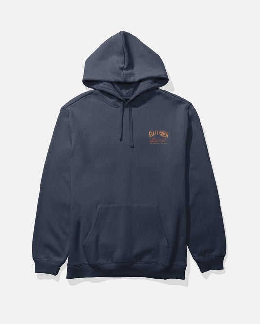 The Island Fleece - Navy by Salty Crew is a navy blue cotton-polyester hoodie featuring a kangaroo pocket and small orange “Salt & Chem” text screenprinted over the left chest. The hoodie is shown laid flat on a light background.
