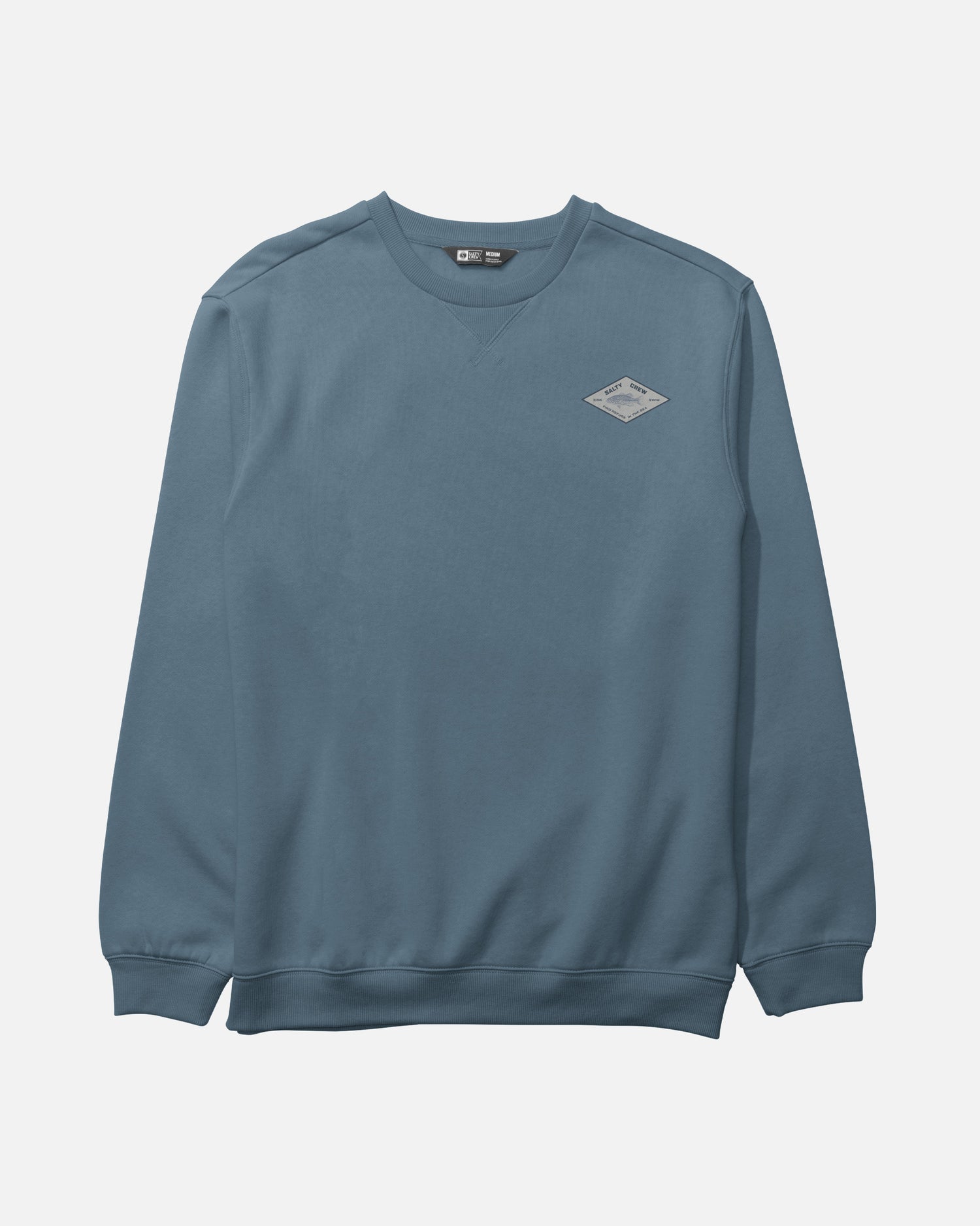 The Salty Crew Crafted Crew Fleece in Slate is a blue crewneck sweatshirt made from a cotton-polyester blend, featuring long sleeves with ribbed cuffs, a classic V-stitch gusset at the neckline, and a small diamond-shaped patch logo on the left chest, shown laid flat on a white background.