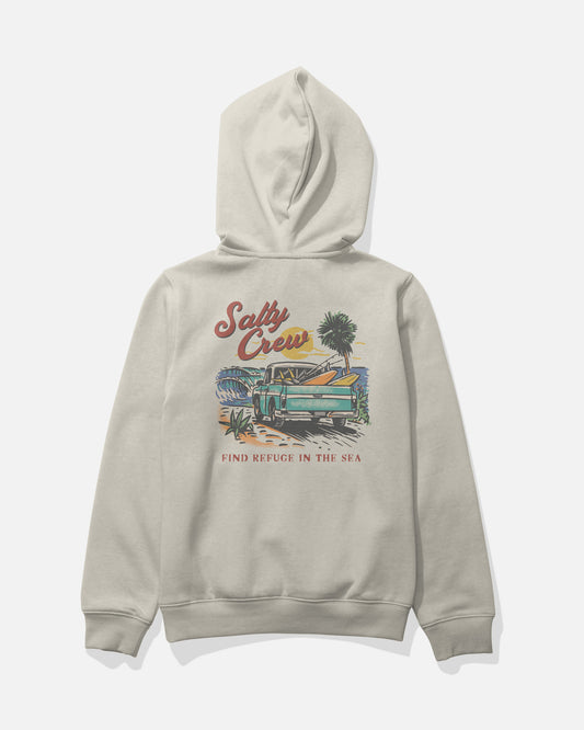 The Salty Crew Truck Bed Boys Fleece in Bone is a mid-weight, light gray cotton-polyester hoodie shown from the back. It features a screenprinted graphic of a vintage truck loaded with surfboards on the beach, set against an ocean backdrop with a palm tree and sunset. The design includes the text “Salty Crew” and “FIND REFUGE IN THE SEA,” combining comfort and style for all your adventures.