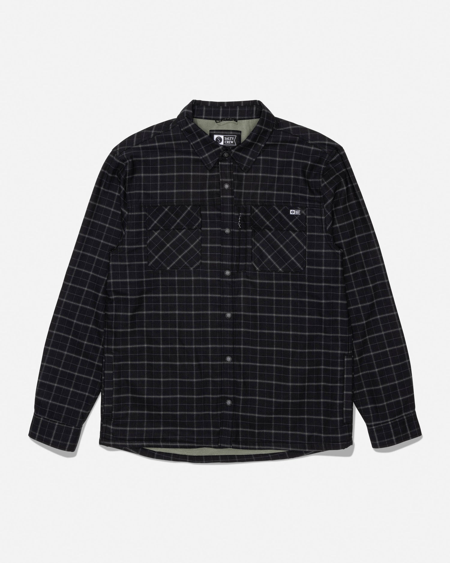 The Salty Crew Fathom Tech Shacket in Black/Green features long sleeves, a button-up front, a white grid pattern over black mid-weight twill fabric, dual chest pockets, and a small logo on the left pocket. The shirt is displayed laid flat on a white background.
