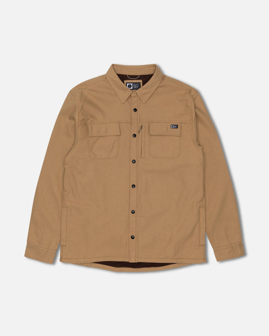 The Salty Crew Fathom Tech Shacket in Khaki features long sleeves, two chest pockets with a small black patch on the left pocket, and black buttons. Crafted from comfortable mid-weight twill for lasting durability, it’s shown here against a plain white background.