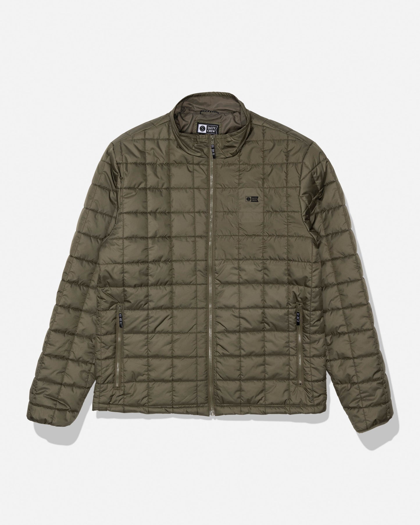 Salty Crew’s Barrier Lite Jacket in Washed Leaf features an olive green quilted design with a zip front, two zippered side pockets, and a small black rectangular logo on the left chest. This jacket includes a simple collar, lightweight synthetic fill for comfort, and padded construction, making it an ideal water-resistant option for everyday wear.