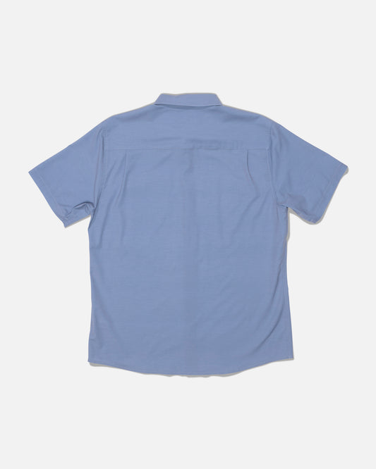The Salty Crew Drifter UV Button Up in Hitch Blue is displayed laid flat with the back side facing up against a plain white background. Featuring UPF 50+ sun protection and moisture-wicking fabric, this short-sleeve collared shirt provides comfort and coverage for sunny days.