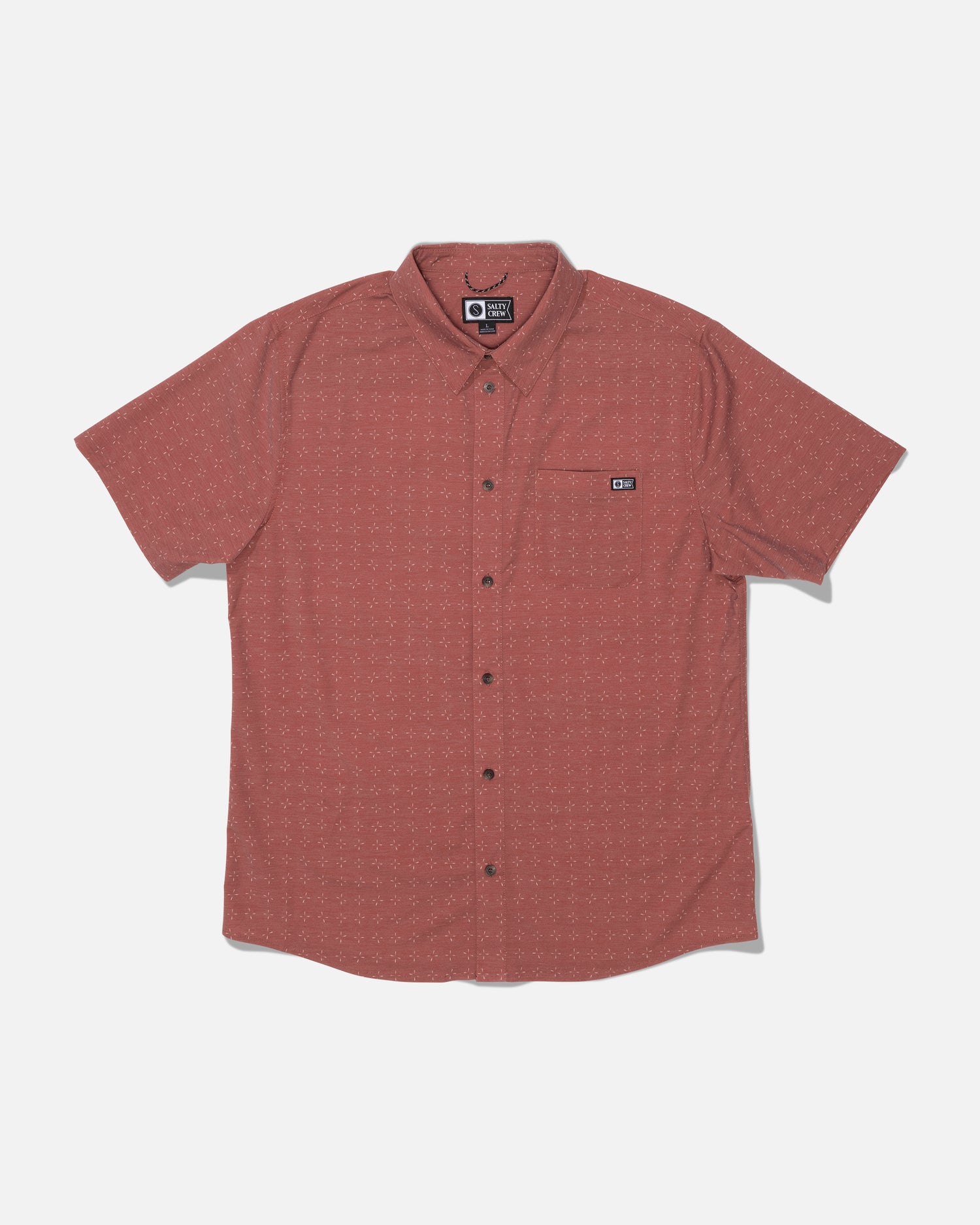 The Salty Crew Drifter UV Button Up in Mid Red is a short-sleeve, button-up shirt featuring a subtle dotted pattern, front chest pocket with a small logo patch, and crafted from moisture-wicking fabric with UPF 50+ sun protection. The shirt is laid flat on a white background.