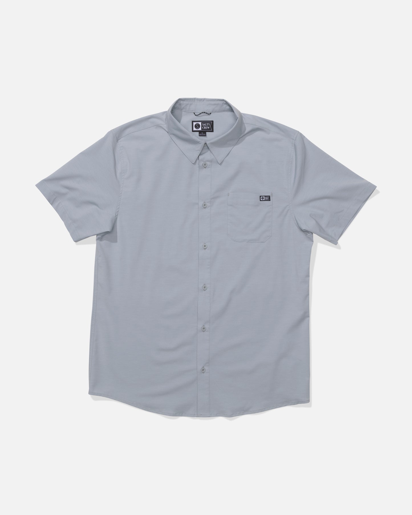 The Salty Crew Drifter UV Button Up in Quarry is a light gray, short-sleeve shirt with a collar, left chest pocket, and small black tag. Made from moisture-wicking fabric, it is shown laid flat on a white background.