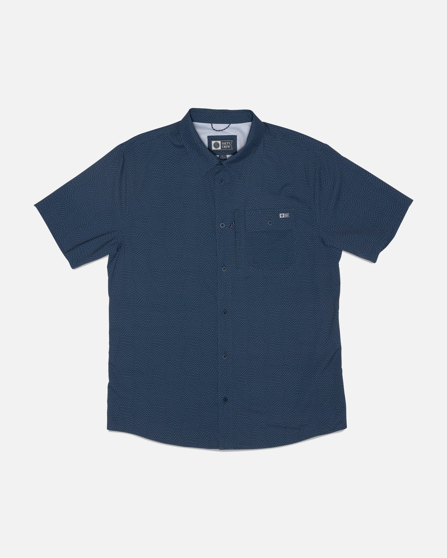 The Salty Crew Flagship UV Button Up in Mid Blue is a short-sleeve shirt featuring a subtle dotted pattern, a single chest pocket with a small logo tag nearby, and is crafted from quick-dry fabric for added comfort. The shirt is displayed laid flat on a white background.