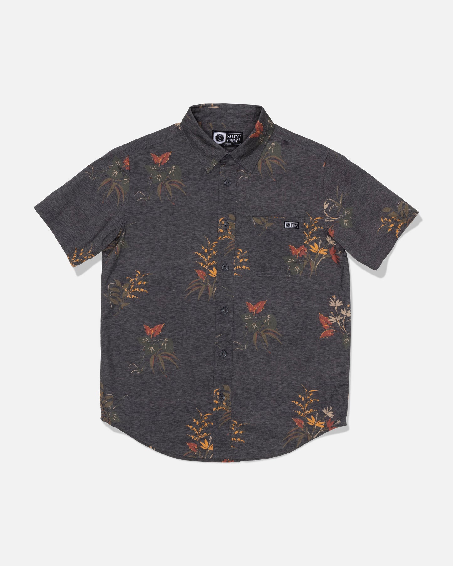 The Salty Crew Boys Button Up - Off Black is a short-sleeve, button-up shirt made from a cotton blend in dark gray, featuring an allover floral and butterfly print. It includes a classic collar and a small chest pocket on the left side with a stitched logo tag. A garment wash finish provides extra softness and comfort.