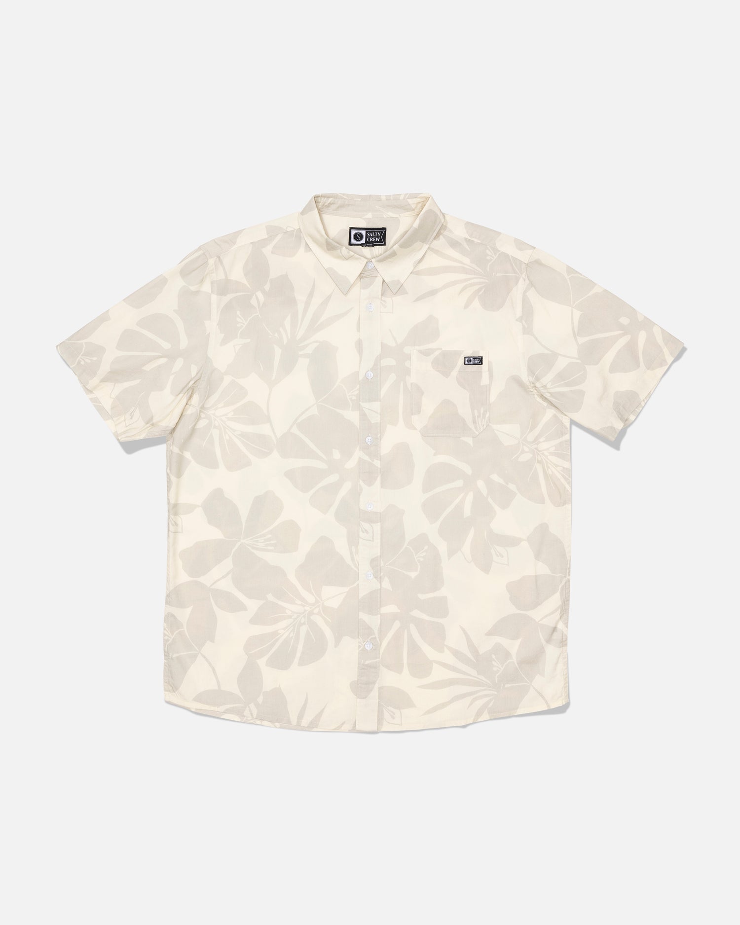 Introducing the Salty Crew Crew Button Up - Birch: a short-sleeve, button-up shirt crafted from a comfortable cotton blend in a cream birch shade. It features a subtle allover leaf print, a small chest pocket detailed with a black and white Salty Crew label, and is finished with a soft garment wash for added comfort.
