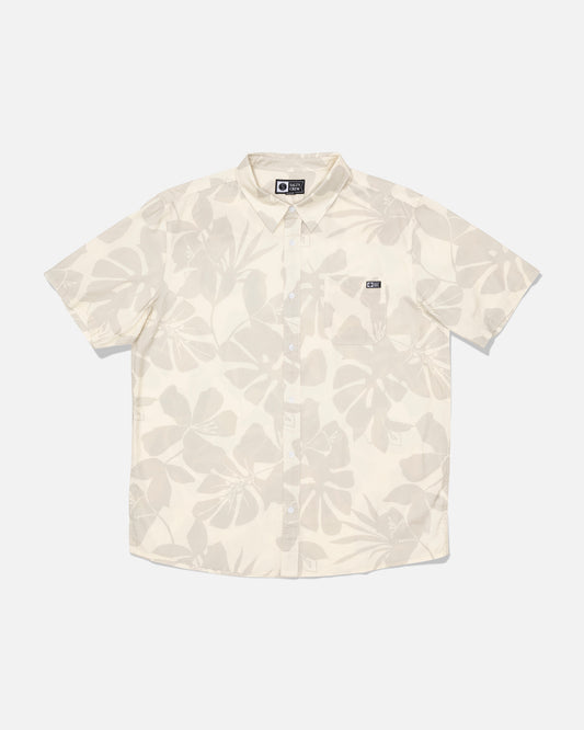 Introducing the Salty Crew Crew Button Up - Birch: a short-sleeve, button-up shirt crafted from a comfortable cotton blend in a cream birch shade. It features a subtle allover leaf print, a small chest pocket detailed with a black and white Salty Crew label, and is finished with a soft garment wash for added comfort.