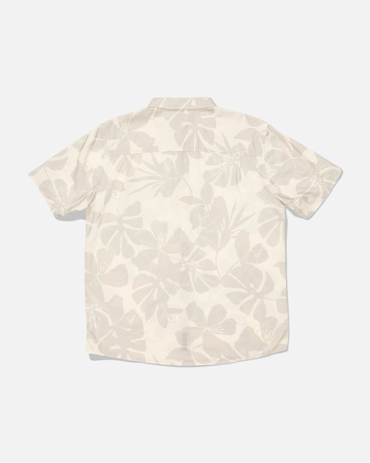The Salty Crew “Crew Button Up - Birch” is a short-sleeve shirt made from a cotton blend, featuring a light beige and white allover floral print. Shown from the back against a plain white background, this shirt has been garment washed for enhanced softness and a relaxed feel.