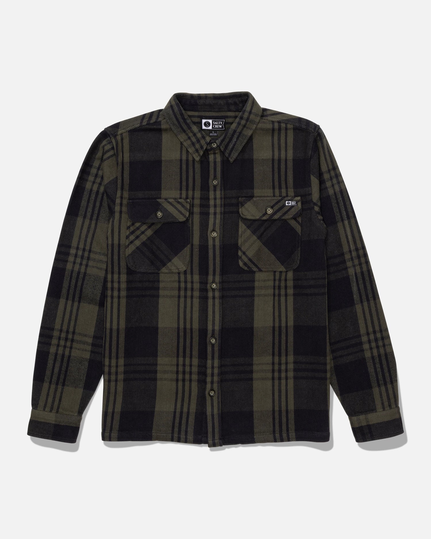 The Salty Crew Windward Flannel in Green/Black is a long-sleeve, button-up shirt featuring a black and olive green plaid pattern. Crafted from heavyweight cotton twill, it includes dual chest pockets with button flaps and branded resin buttons. The shirt is displayed laid flat on a white background.