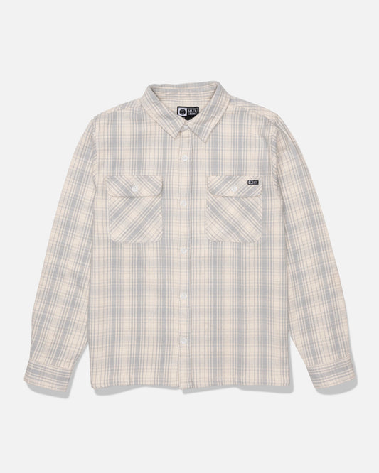 The Salty Crew Windward Flannel in Off White is a beige and light gray plaid button-up shirt, crafted from heavyweight cotton twill with a garment wash finish. It features two chest pockets and long sleeves, and is displayed on a white background.
