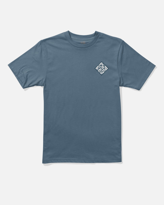 The Salty Crew Tippet Fill Boys Tee in Slate Blue is a short-sleeve shirt made from combed ringspun 100% cotton, featuring a small white and blue diamond-shaped graphic screenprinted on the left chest. The background is plain white.