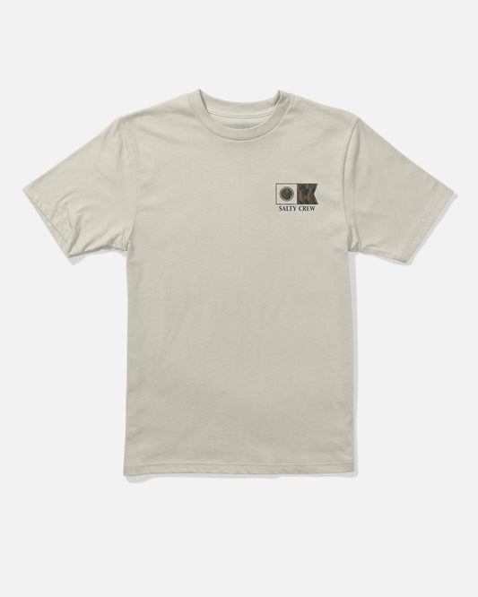 The Salty Crew Flagship Boys Tee in Bone is a beige short-sleeve combed ringspun cotton t-shirt featuring a small screenprinted fish and circular graphic with the text “Salty Crew” on the left chest. The shirt is displayed laid flat on a white background.