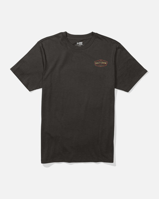 The Salty Crew Tailfin Crew Tee in black is a combed ringspun cotton t-shirt featuring a small, circular Salt Crew logo in orange and white screenprinted on the left chest. The shirt is displayed laid flat on a white background.