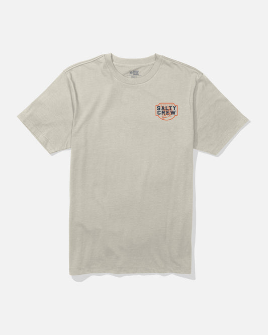 The Red Drum Crew Tee - Bone by Salty Crew is a beige short-sleeve combed ringspun cotton t-shirt featuring a small Salty Crew logo with a red circular border and block lettering on the left chest. The shirt is displayed laid flat on a white background.