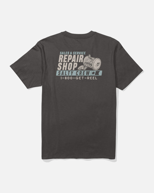 Back of the Salty Crew Reel Repair Crew Tee in dark grey, crafted from 100% combed ringspun cotton, displays a screenprinted fishing reel graphic along with the text “SALES & SERVICE REPAIR SHOP SALTY CREW 1-800-GET-REEL” in white and teal lettering.