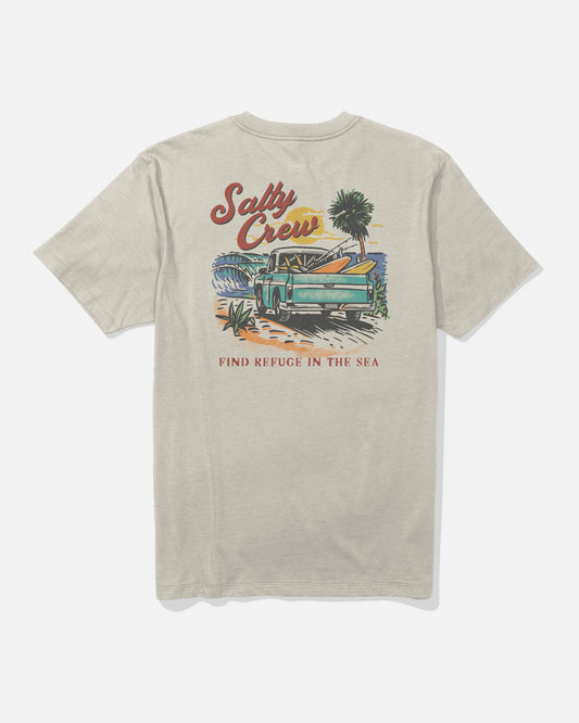 The Truck Bed Crew Tee - Bone by Salty Crew is a beige combed ringspun cotton t-shirt featuring a screenprinted graphic of a green truck with surfboards, palm trees, and beach scenery. The text “Salty Crew” appears at the top and “Find Refuge in the Sea” at the bottom.