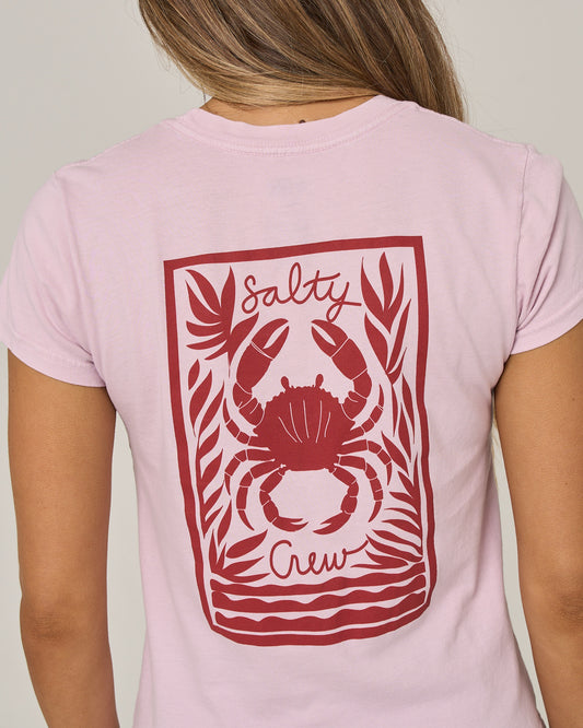 A person is shown from behind wearing the Salty Crew Crabby Modern Tee in Pale Orchid, a fitted cotton jersey shirt featuring a red graphic of a crab and seaweed with “Salty Crew” on the back.