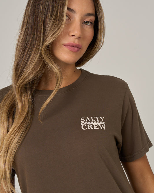 A woman with long, wavy blonde hair is wearing the Salty Crew Lobster Roll Boyfriend Tee in washed brown—a short sleeve cotton jersey t-shirt featuring white “Salty Crew” text on the chest—while standing against a neutral gray background.