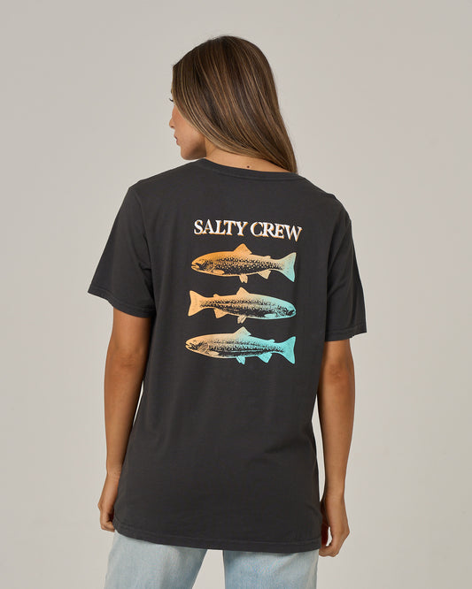 A woman is seen from behind wearing the Salty Crew Daily Catch Boyfriend Tee in charcoal, a relaxed fit cotton jersey t-shirt with short sleeves. The shirt features “SALTY CREW” above a vertical graphic of three trout, each illustrated in unique orange and blue gradient hues.