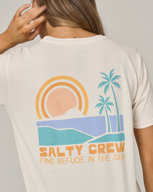 Wearing the Salty Crew Sushi Roll Boyfriend Tee in Off White, this relaxed-fit cotton jersey t-shirt features short sleeves and a coastal-inspired graphic of a sun, mountains, ocean, and palm trees. The front displays the text “SALTY CREW FIND REFUGE IN THE SEA,” offering comfortable style perfect for seaside adventures.