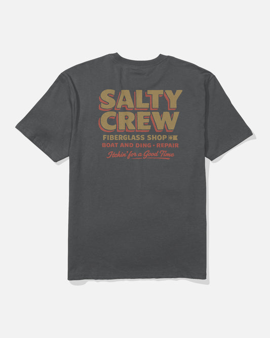 The Salty Crew Fiberglass Heavyweight Tee in washed black features large retro-style "SALTY CREW FIBERGLASS SHOP BOAT AND DING REPAIR" text on the back, with smaller script below reading "Itchin’ for a Good Time.