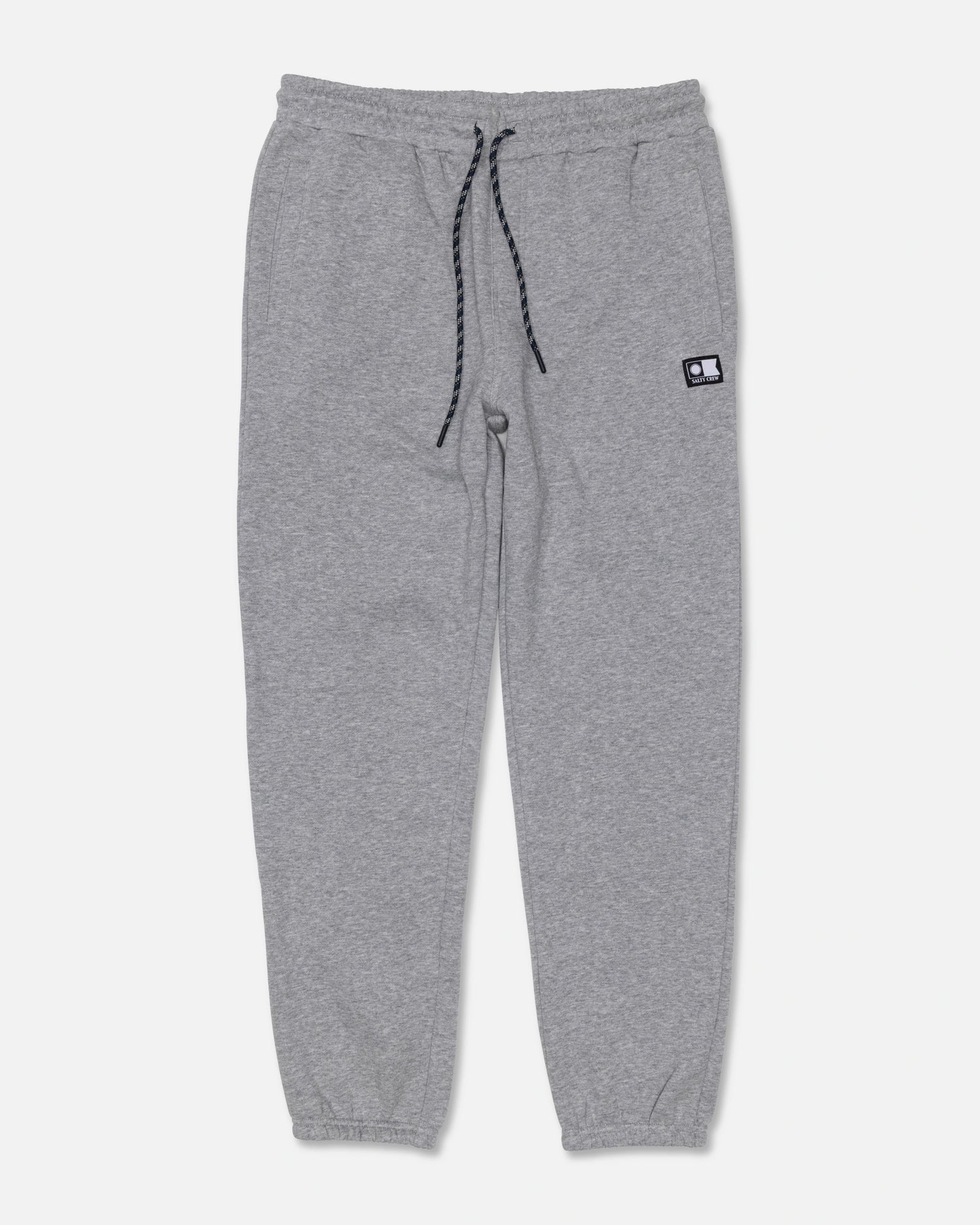 The Salty Crew Crewser Fleece Pant in Athletic Heather features light gray sweatpants crafted from a soft cotton-polyester blend, with an elastic waistband, black drawstring, cuffed ankles, and side pockets. A small rectangular black-and-white patch appears on the left thigh. Displayed on a plain white background.