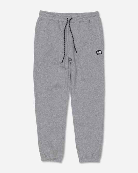 The Salty Crew Crewser Fleece Pant in Athletic Heather features light gray sweatpants crafted from a soft cotton-polyester blend, with an elastic waistband, black drawstring, cuffed ankles, and side pockets. A small rectangular black-and-white patch appears on the left thigh. Displayed on a plain white background.