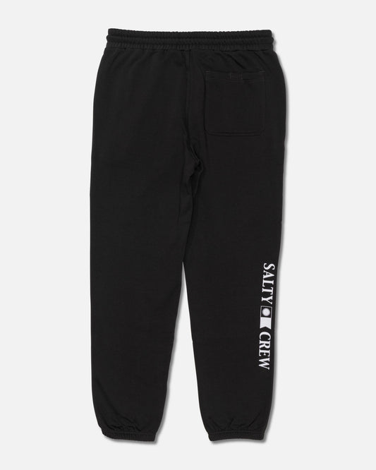 The Salty Crew Crewser Fleece Pant in Pirate Black features an elastic waistband and cuffs, a back pocket, and “SALTY CREW” screenprinted vertically in white on the left leg. The pants are displayed laid flat on a white background.