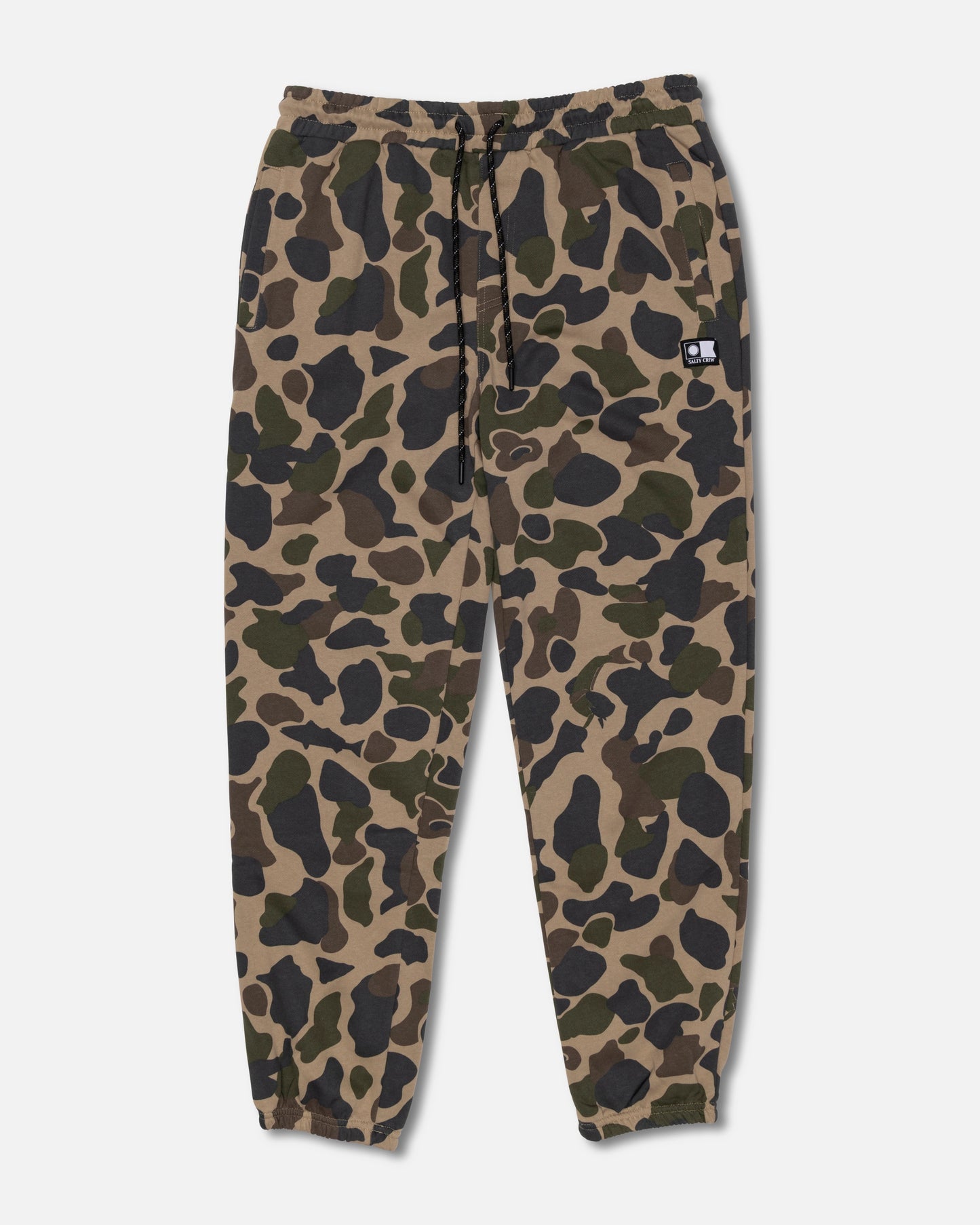 The Salty Crew Crewser Fleece Pant in Sand Camo features an elastic waistband with a drawstring, elastic cuffs, convenient side hand pockets, and a small black patch on one front pocket. The pants showcase a green, brown, and black camouflage pattern.