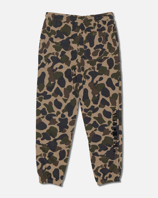 Salty Crew Crewser Fleece Pant in Sand Camo features a camouflage pattern, elastic waistband and cuffs, side hand pockets, a back pocket, and “Salty Crew” text printed vertically on one leg.