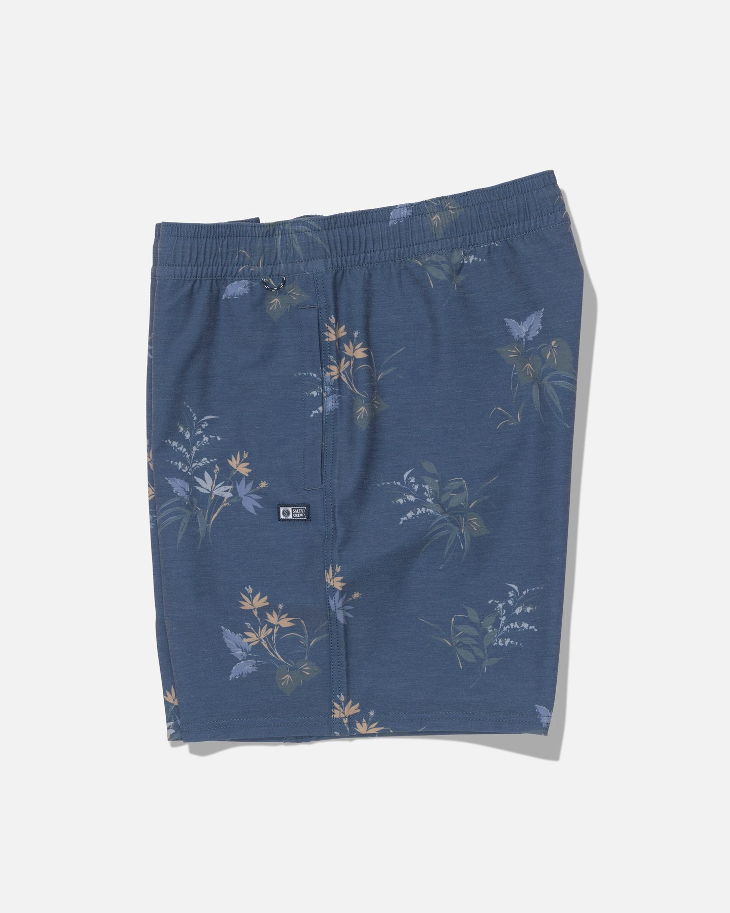 The Salty Crew Crew Volley 17″ shorts in Mid Blue feature a straight leg and an elastic waistband, adorned with a subtle floral and butterfly print in light yellow, green, and white tones. Made from recycled polyester with 4-way stretch for enhanced comfort and flexibility, these shorts are displayed flat against a plain white background.