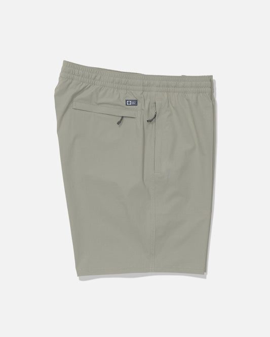 Salty Crew’s Crew 18″ Ewaist Boatshort in Aqua Grey, shown laid flat on a white background, is made from quick-dry ripstop fabric with 4-way stretch for maximum comfort. These light gray athletic shorts feature an elastic waistband, a zipper back pocket, and a subtle Salty Crew logo patch above the pocket.