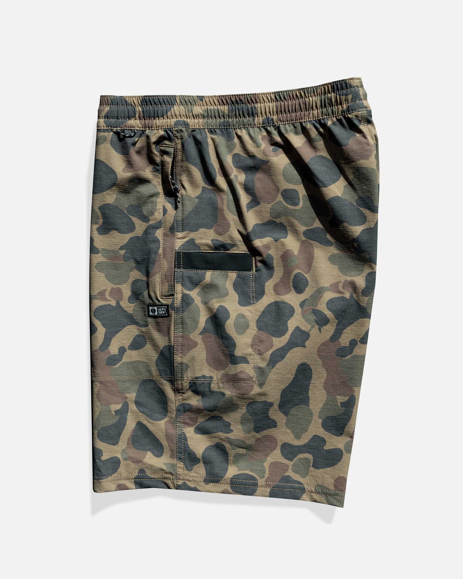 The Salty Crew Crew 18" Boatshort Ewaist in Sand Camo features a green, brown, and black camo pattern, quick-dry ripstop fabric, elastic waistband, front zipper pocket, and side patch pocket.