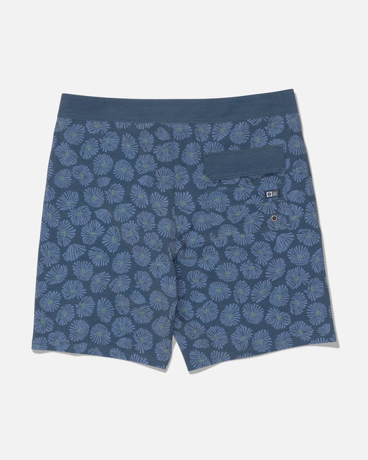 The Salty Crew Crew 19″ Boardshort in Hitch Blue is shown from the back, featuring a light blue and green floral pattern. Made from recycled polyester with 4-way stretch for enhanced comfort, these boardshorts have a straight leg cut. They include a single right-side pocket with a button flap and a small grommet for drainage.