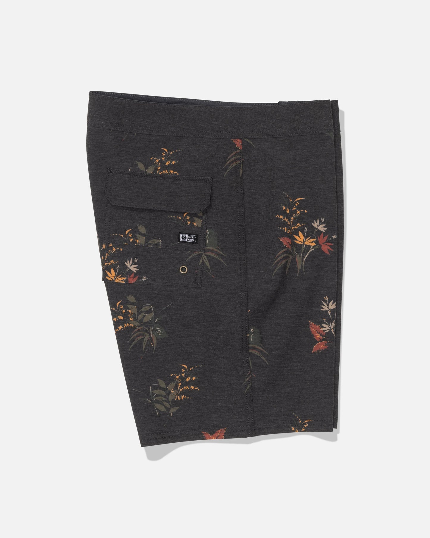 Salty Crew’s Crew 19″ Boardshort in Off Black features a subtle earth-toned floral print on dark gray recycled polyester comfort fabric for an eco-friendly feel. Designed with a back flap pocket secured by a button and finished with a small black Salty Crew brand tag, these stylish and sustainable boardshorts are shown flat against a white background.