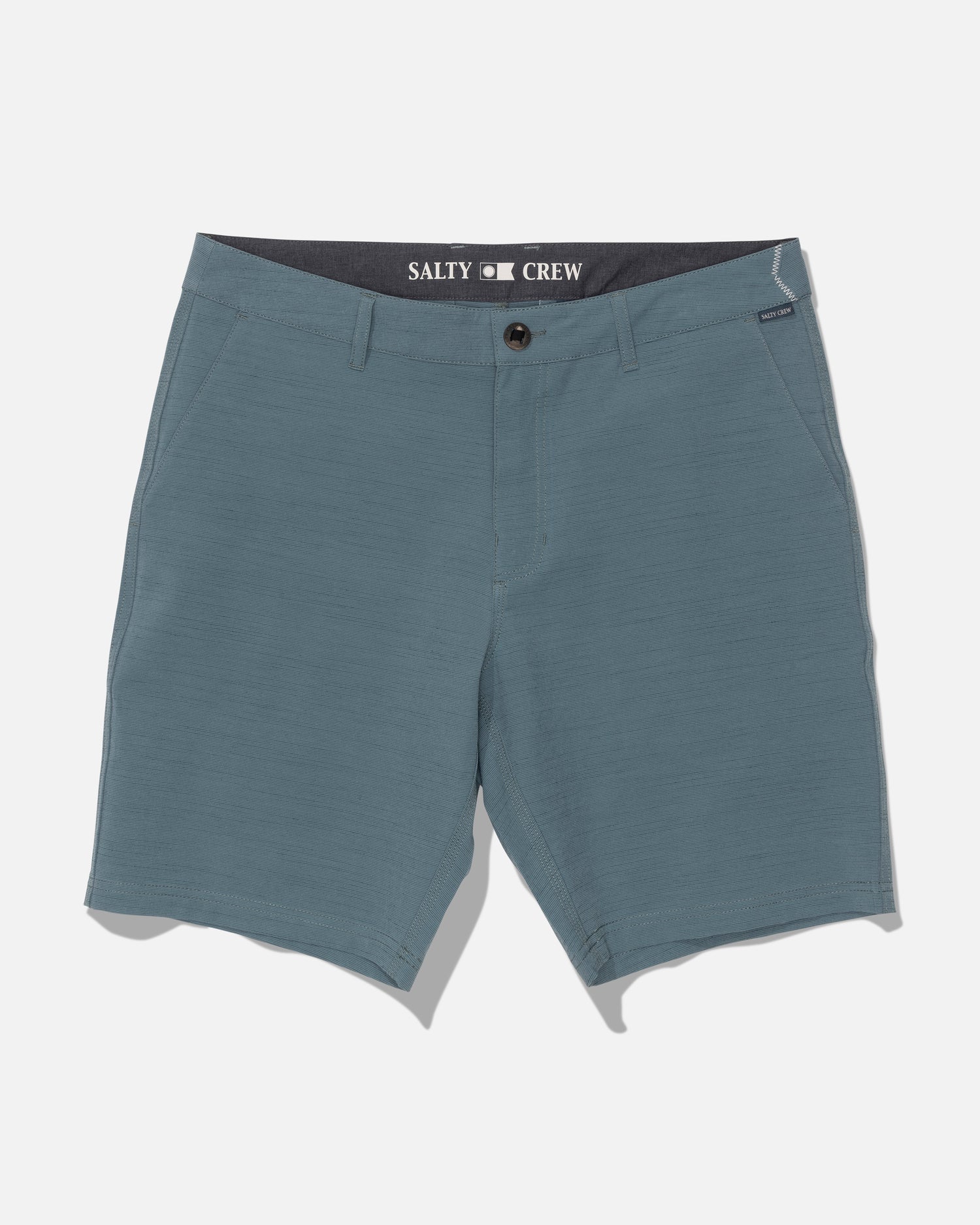 Salty Crew Drifter 19″ Slub Hybrid shorts in Mid Ocean are men’s blue shorts featuring belt loops, front pockets, and a button closure. Made from recycled performance fabric with 4-way stretch for optimal comfort and freedom of movement, these shorts are built for your active lifestyle. Quick-dry technology helps you stay cool and comfortable throughout the day. “Salty Crew” is printed inside the waistband, and the shorts are displayed laid flat on a white background.