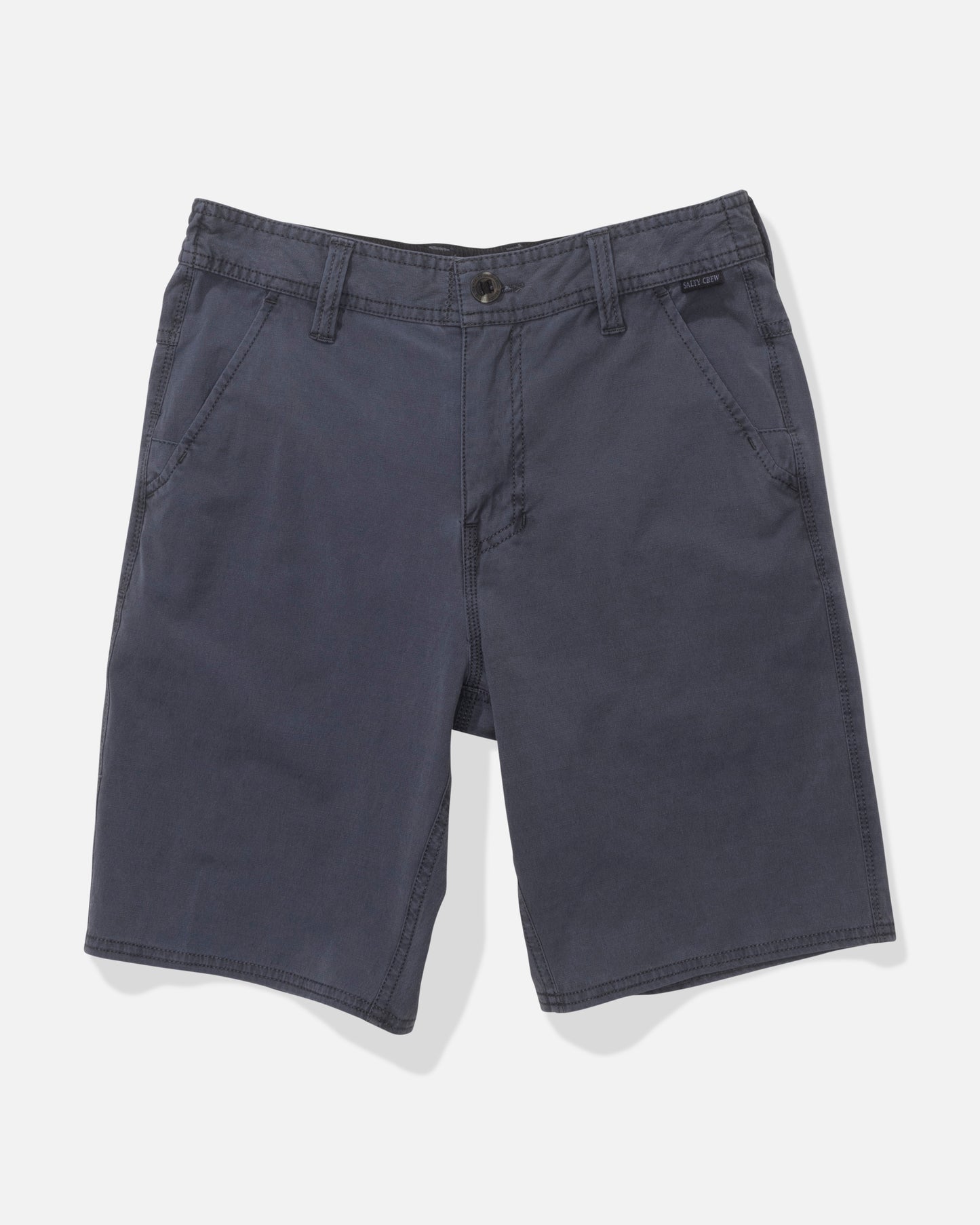 The Salty Crew Transom 17" Boys Overdye Short in Magnet is a pair of dark blue, straight-leg shorts with 4-way stretch, front pockets, belt loops, and a button closure, shown flat on a white background.