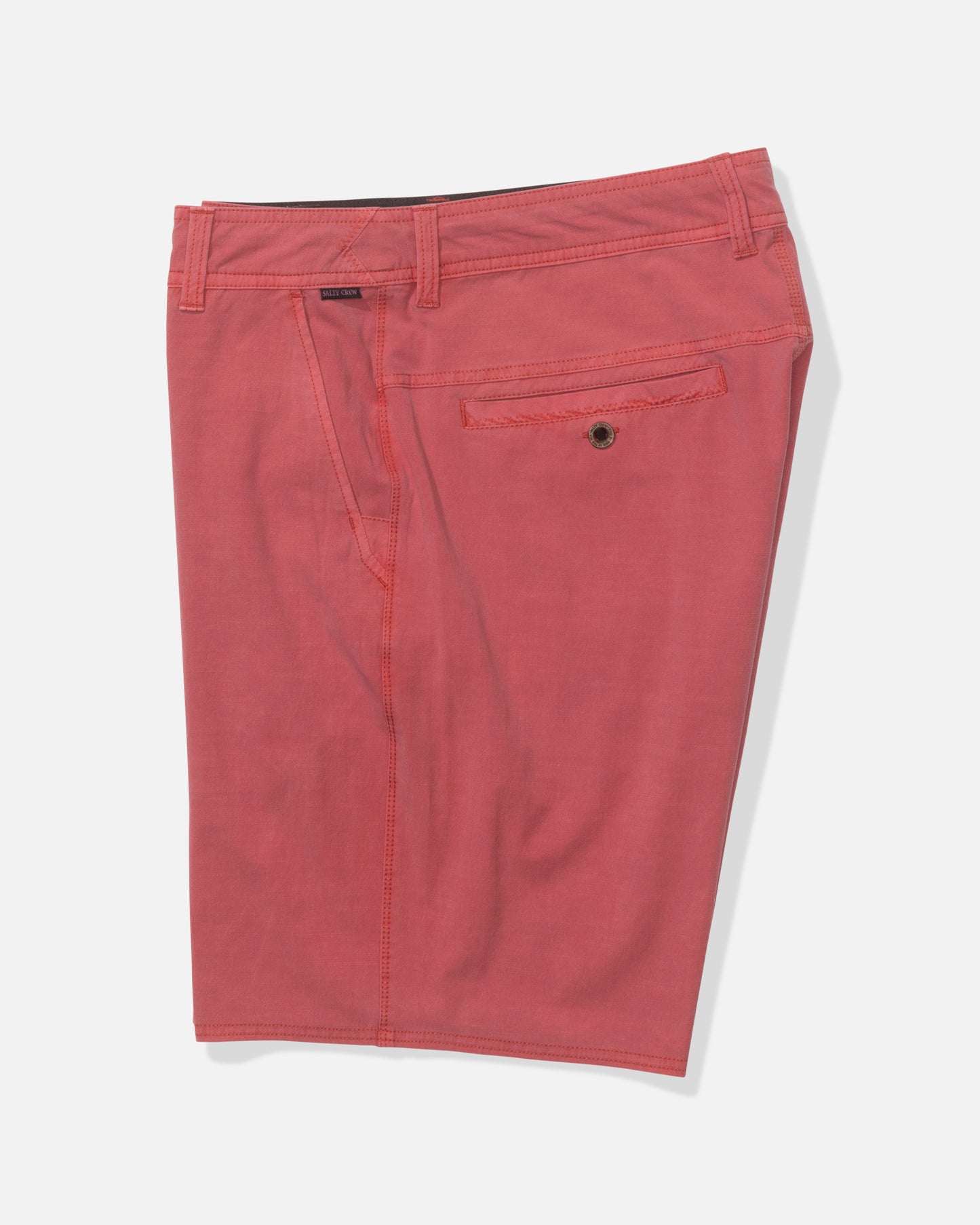 The Salty Crew Transom 19" Overdye Short in Baked Apple features knee-length, 4-way stretch fabric, belt loops, side pockets, and a buttoned back pocket, shown on a white background.
