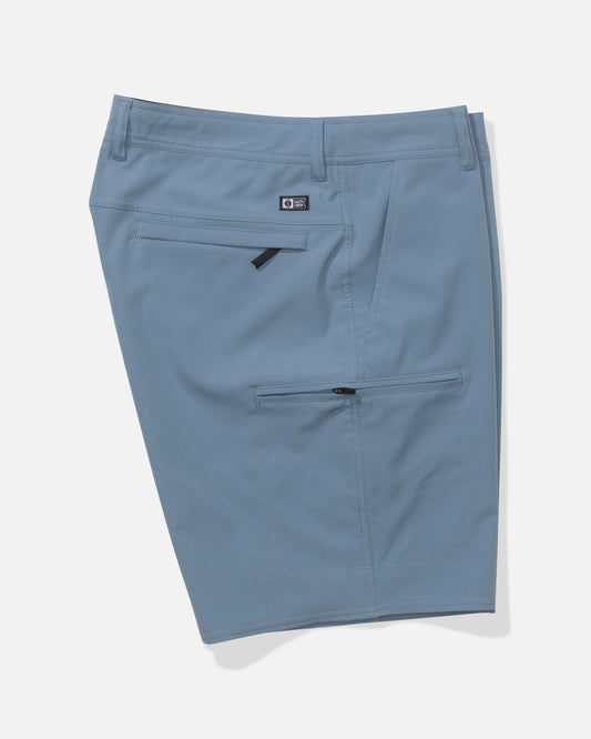 The Salty Crew Transom 19" Tech Short in Pilot Blue is a light blue, knee-length short made from lightweight, quick-dry fabric with belt loops, a small logo above the rear zip pocket, and an extra horizontal zip pocket below.