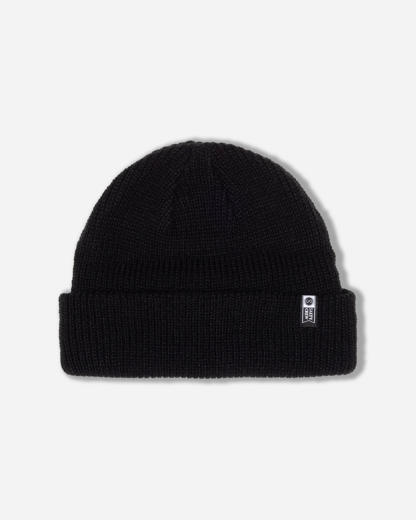 The Salty Crew Alpha Beanie in Off Black features a folded brim and a small rectangular woven label on the front right side, and is shown against a plain white background.