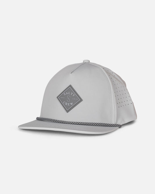 The Long Range Snapback - Harbor Grey by Salty Crew features a light gray polyester construction with a structured, water-resistant design. This snapback hat showcases a flat brim, a diamond-shaped Salty Crew logo patch on the front, perforated side panels for breathability, and a braided rope detail along the brim. The background is plain white.
