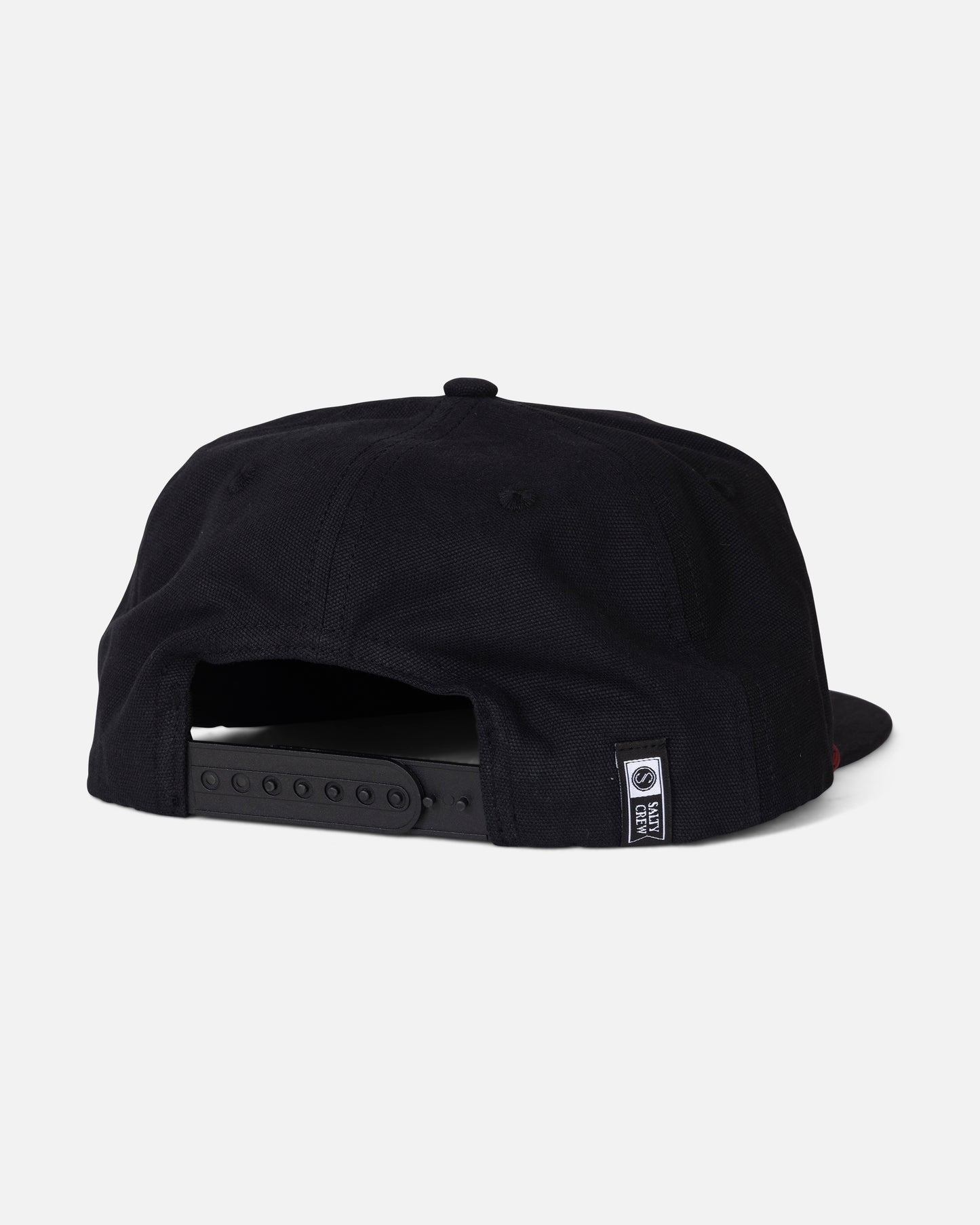 The Salty Crew Coastal Snapback - Black is displayed from the back against a plain white background. Made from durable cotton canvas, it features a five-panel design, an adjustable snapback strap, and a small black-and-white Salty Crew tag near the opening.