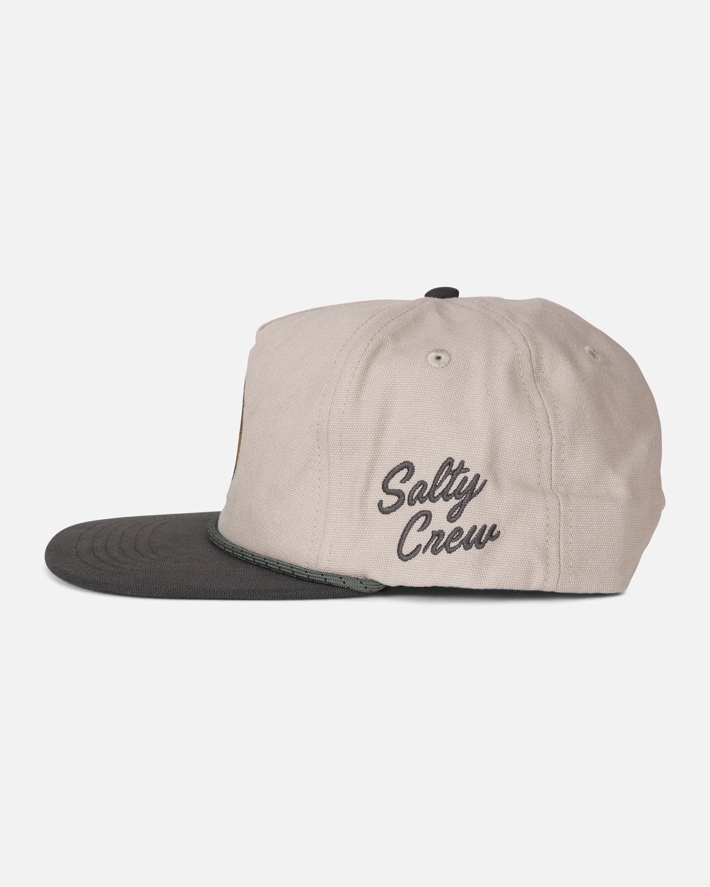 A side view of the Salty Crew Coastal Snapback in Grey/Tan shows a light beige cotton 5-panel cap with a dark charcoal brim and rope detail. “Salty Crew” is embroidered in black cursive on the side of this mid crown hat, set against a plain white background.